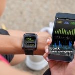 Female Runner Looking At Her Mobile And Smart Watch Heart Rate Monitor
