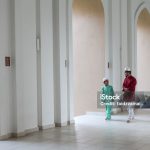 A Malay Muslim father and his son walking together in a mosque, wearing a traditional Malay dress for men, heading towards the prayer hall.