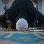 Close-up shot of a Muslim young man worshiping in a mosque. Horizontal composition.