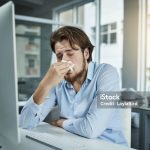 Shot of a young businessman blowing his nose in an office