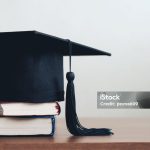 graduation cap on a stack of books with empty space to the right.Graduation concept