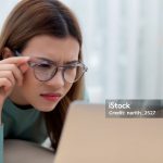 Concentrated young asian woman wearing glasses working on laptop with commitment and ambition sitting on sofa in living room at home, work from home, freelance working online, business and lifestyle.