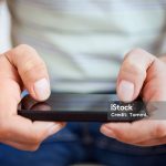 Hands of a casual man using a smartphone.